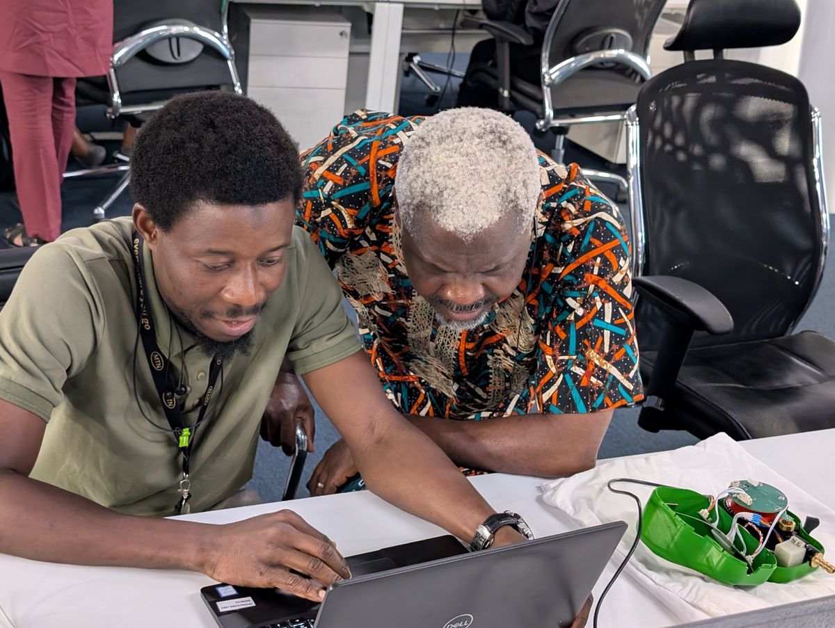 An MTN engineer and a Safi engineer reviewing an opened Kibo meter on the bench